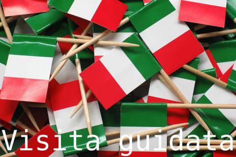 Das Bild zeigt italienische Flaggen und die Worte "Visita guidata" was auf Deutsch Führung oder geführte Tour bedeutet.
