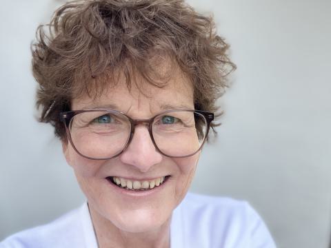 Frau mit dunklen Locken lächelt die Betrachter an